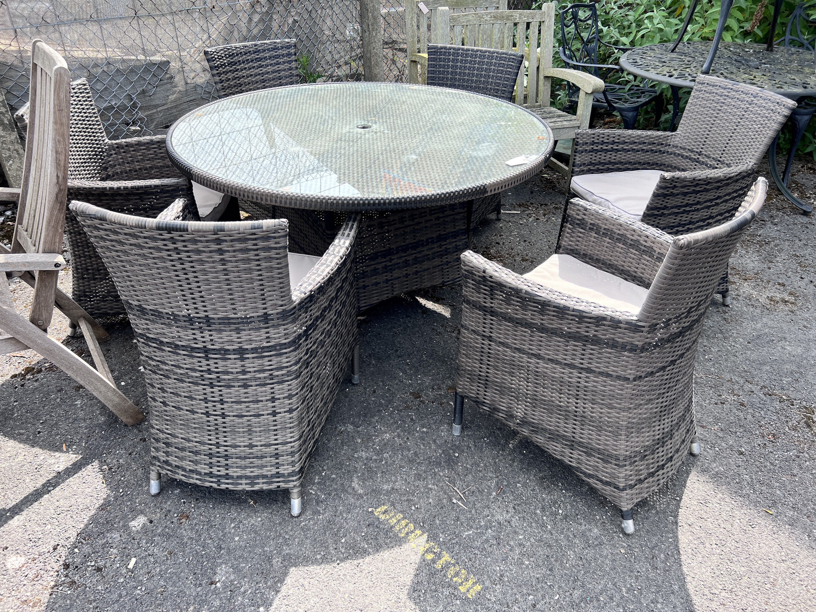 An all weather circular rattan garden table and six chairs with seat cushions, table 136cm diameter, height 75cm